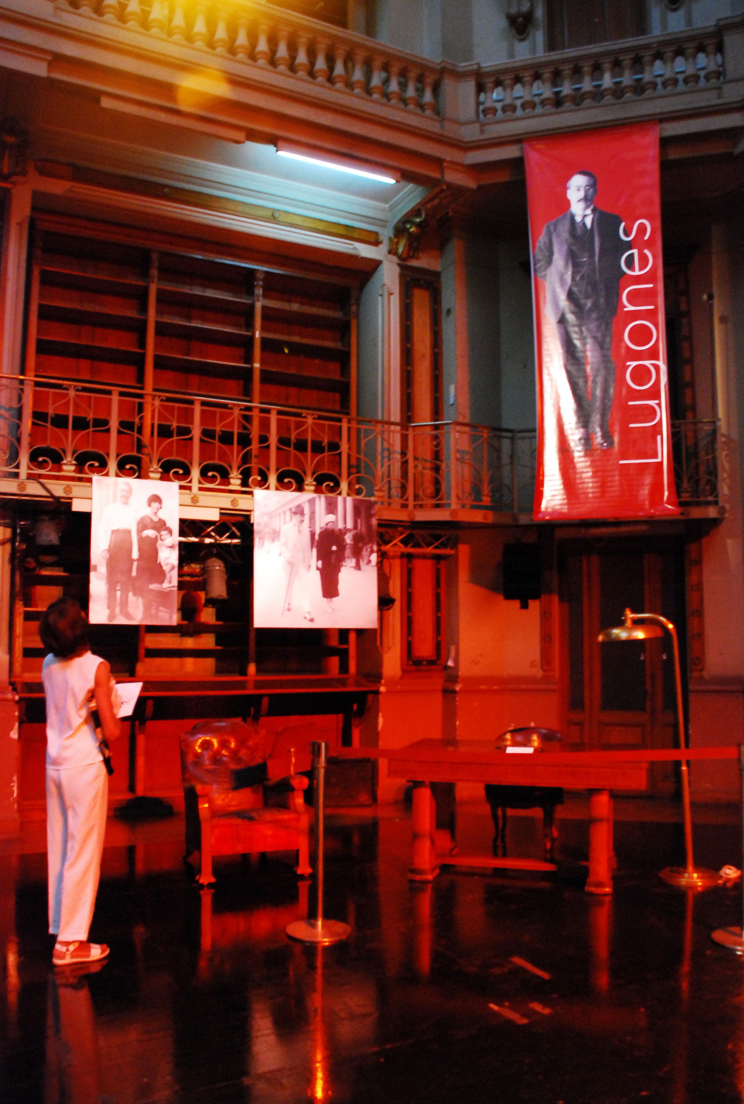 Fotografía de la exposición realizada con motivos del 80 aniversario del fallecimiento de Leopoldo Lugones. Muestra el escritorio del escritor, el sillón, fotos y una persona mirando la exposición.